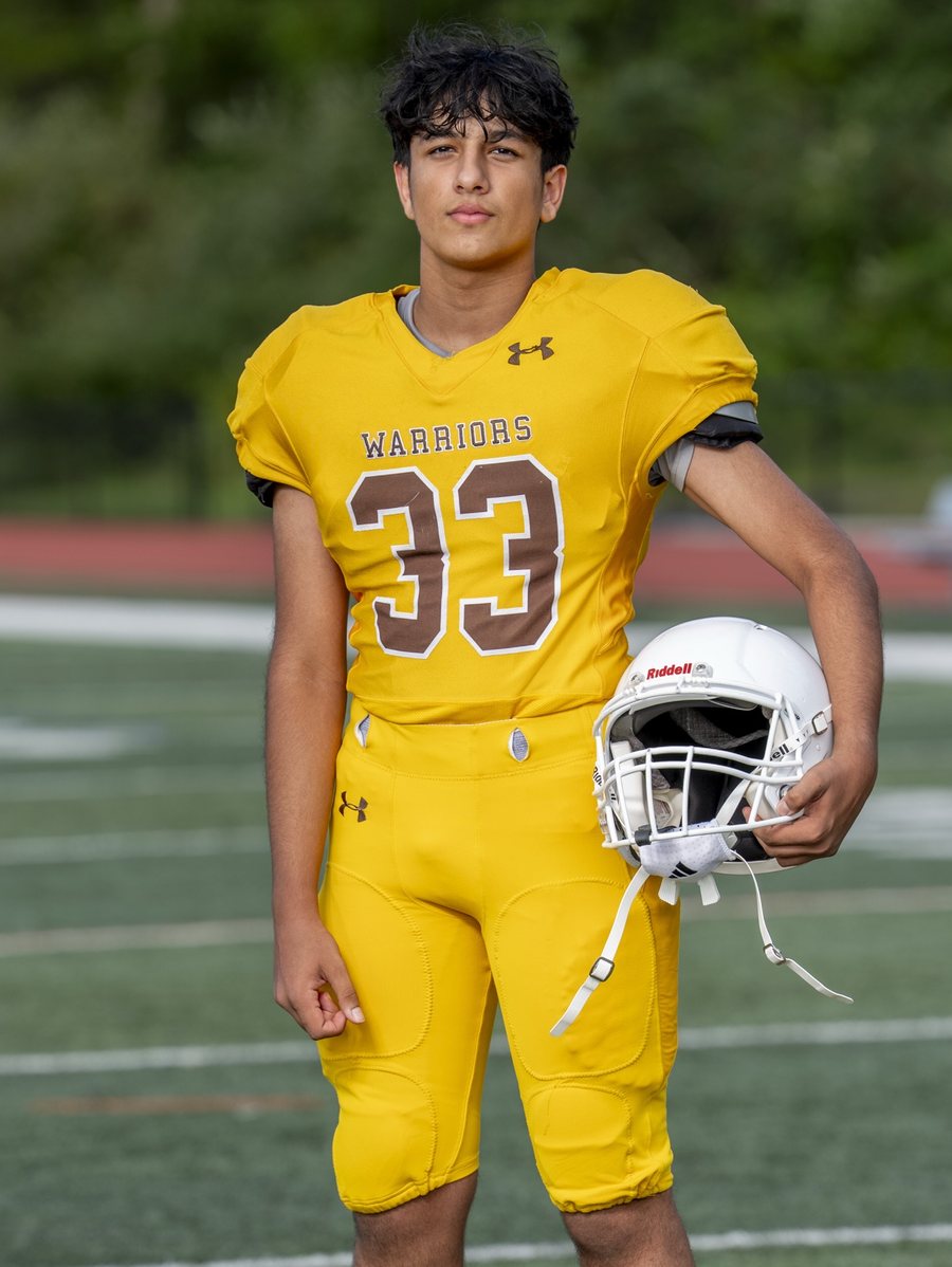 Vir Patel in his school football uniform, number 33, holding
                his helmet on the field